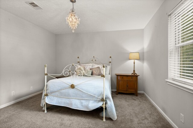 carpeted bedroom with a textured ceiling and a chandelier