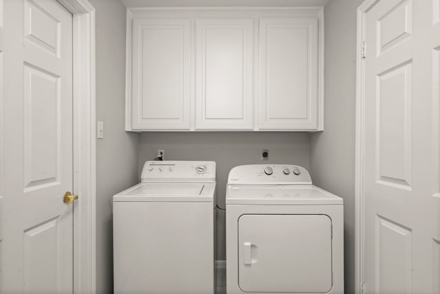 clothes washing area with washer and clothes dryer and cabinets