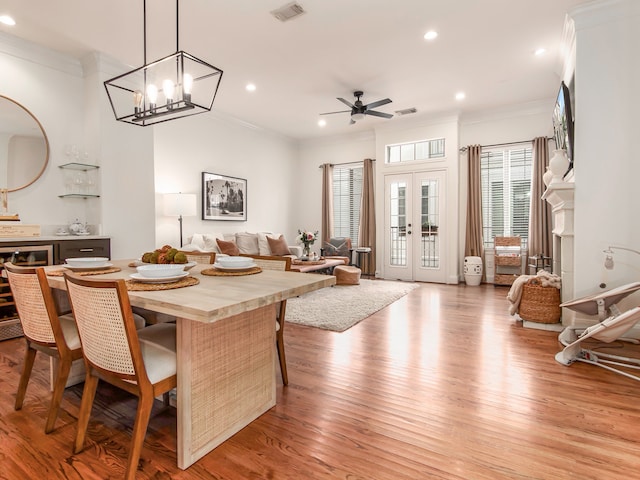 dining area with ceiling fan with notable chandelier, ornamental molding, plenty of natural light, and light hardwood / wood-style flooring