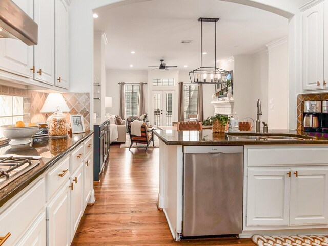 kitchen featuring decorative light fixtures, range hood, sink, stainless steel dishwasher, and light hardwood / wood-style floors