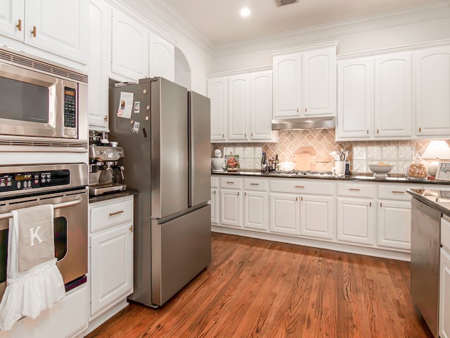 kitchen featuring crown molding, dark wood-type flooring, stainless steel appliances, and white cabinetry