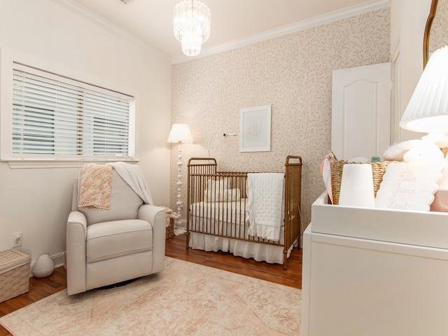 bedroom with ornamental molding, a crib, a chandelier, and light hardwood / wood-style floors