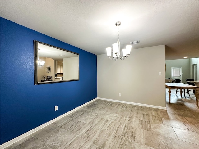 spare room featuring a textured ceiling and a chandelier