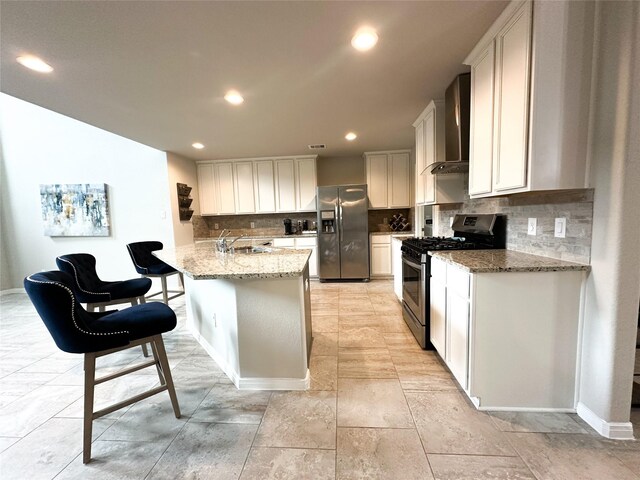 kitchen featuring wall chimney exhaust hood, tasteful backsplash, stainless steel appliances, and white cabinets