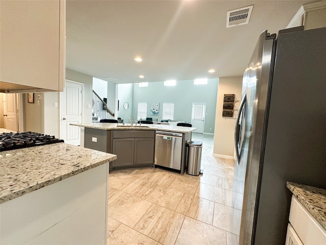 kitchen with light stone counters, gray cabinetry, sink, and appliances with stainless steel finishes