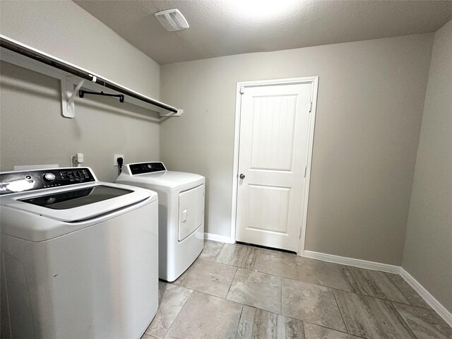 washroom with washing machine and clothes dryer and a textured ceiling