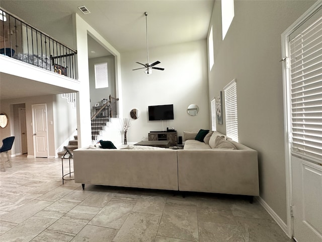 living room with plenty of natural light, ceiling fan, and a high ceiling