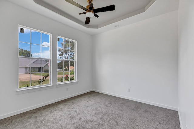 carpeted empty room featuring ceiling fan and a tray ceiling