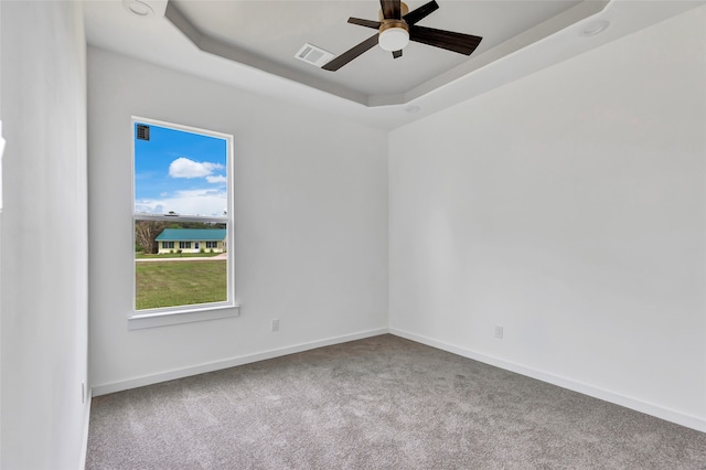 spare room featuring ceiling fan, carpet floors, and a tray ceiling