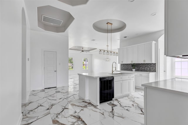 kitchen with decorative light fixtures, a center island with sink, sink, white cabinetry, and ceiling fan