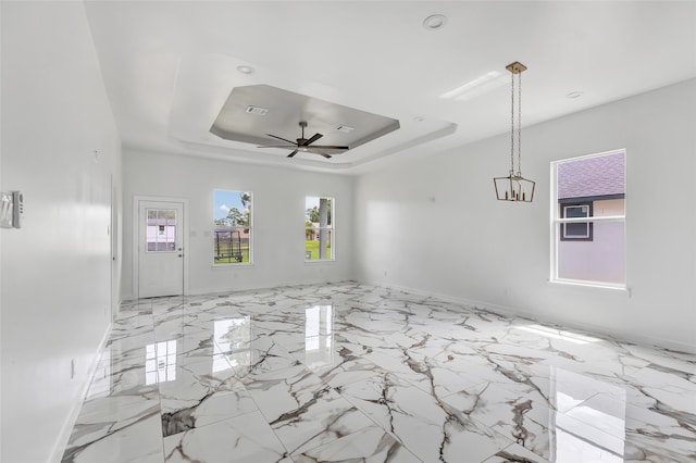 unfurnished room featuring a raised ceiling and ceiling fan