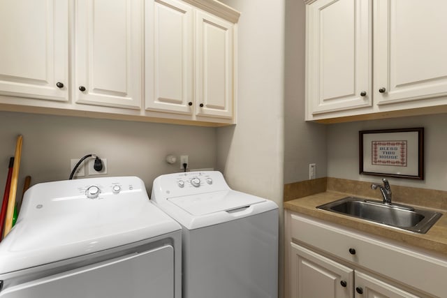 clothes washing area with cabinets, washer and clothes dryer, and sink