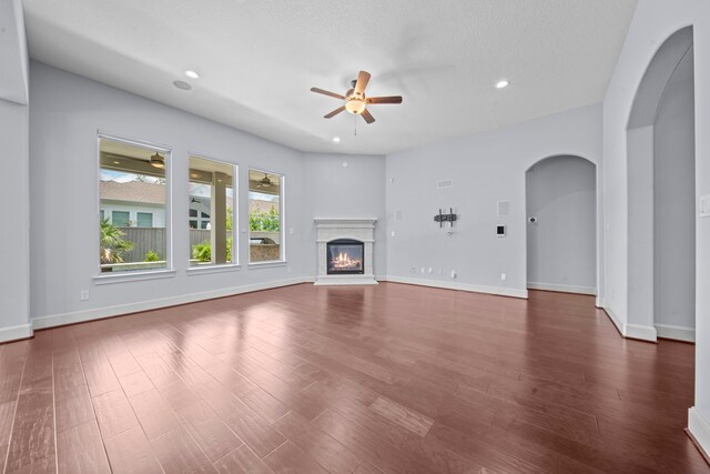 unfurnished living room featuring ceiling fan, dark hardwood / wood-style flooring, and a textured ceiling