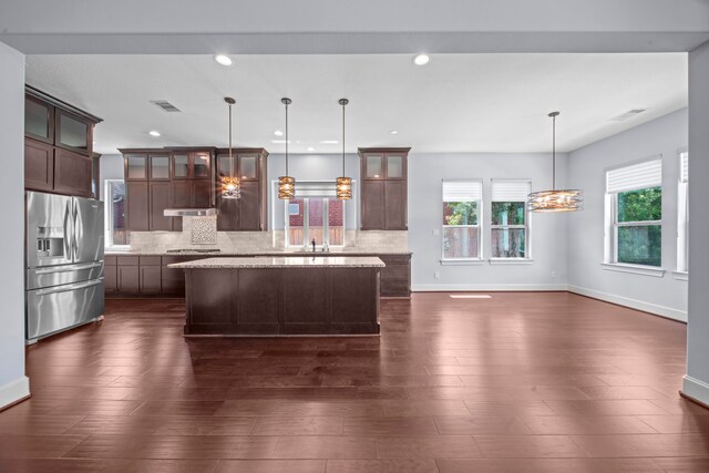 kitchen featuring a kitchen island, dark hardwood / wood-style floors, light stone counters, hanging light fixtures, and appliances with stainless steel finishes