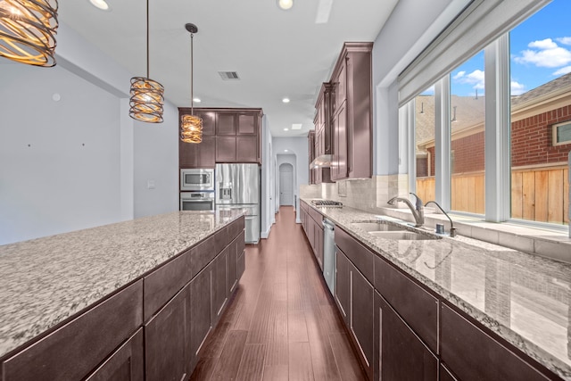 kitchen featuring pendant lighting, dark wood-type flooring, sink, stainless steel appliances, and backsplash