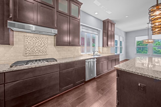 kitchen featuring light stone counters, tasteful backsplash, dark wood-type flooring, pendant lighting, and appliances with stainless steel finishes