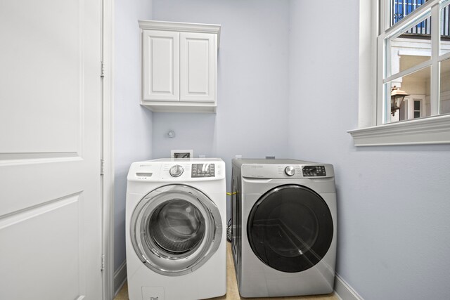 clothes washing area with washer and clothes dryer and cabinets