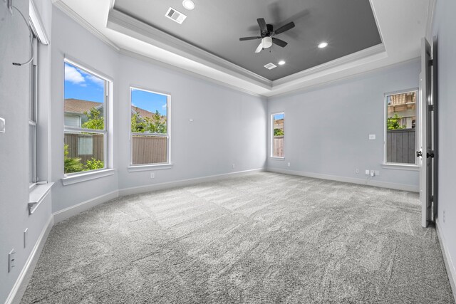 carpeted empty room featuring ceiling fan, a raised ceiling, and ornamental molding