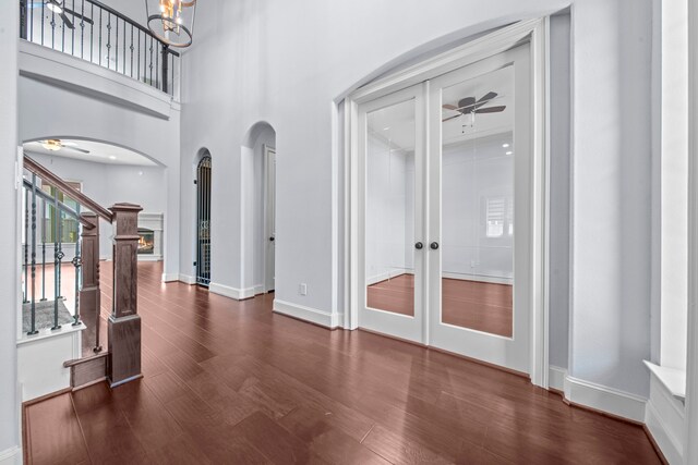 entryway featuring ceiling fan with notable chandelier, dark hardwood / wood-style floors, and a high ceiling