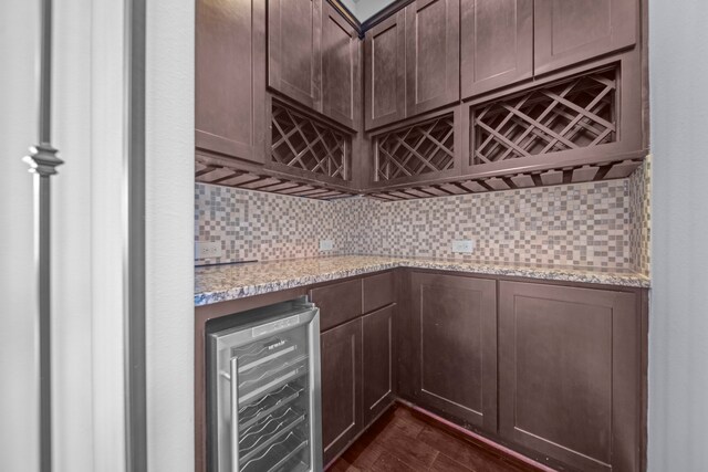 interior space featuring light stone countertops, wine cooler, dark hardwood / wood-style flooring, and backsplash