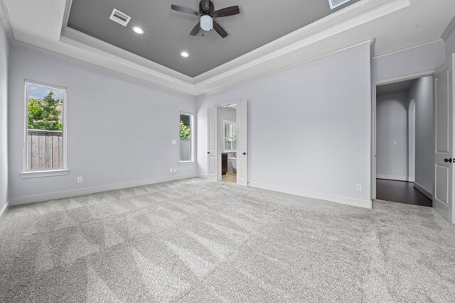 carpeted empty room with ornamental molding, a tray ceiling, and ceiling fan