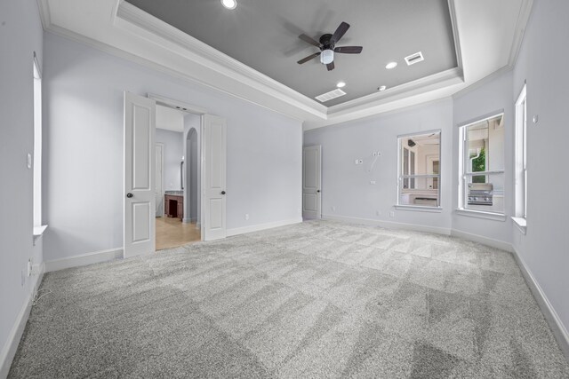 carpeted spare room with ornamental molding, ceiling fan, and a tray ceiling