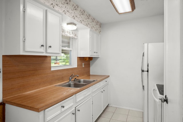 kitchen with light tile patterned flooring, white appliances, white cabinetry, and sink