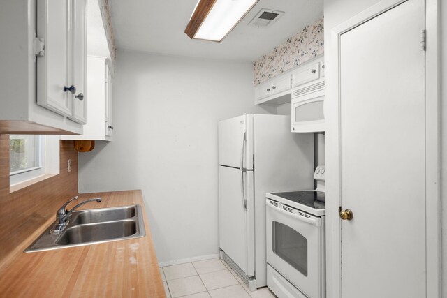 kitchen with white cabinetry, light tile patterned floors, white appliances, and sink