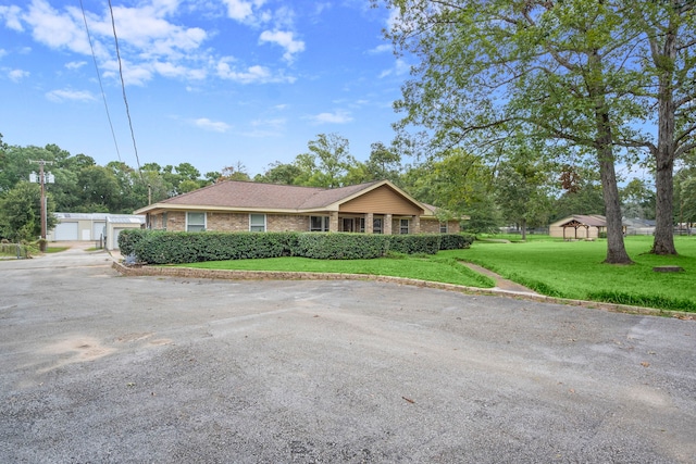 single story home featuring an outdoor structure, a garage, and a front lawn