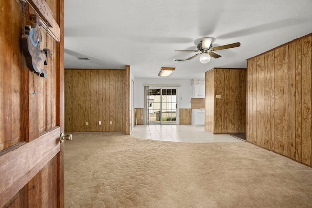 unfurnished living room featuring light colored carpet, wood walls, and ceiling fan