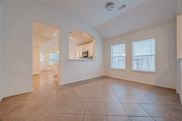 tiled spare room with vaulted ceiling