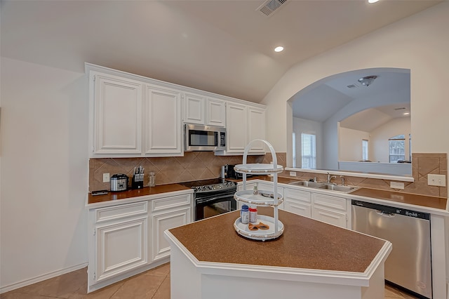 kitchen with a kitchen island, stainless steel appliances, sink, and vaulted ceiling