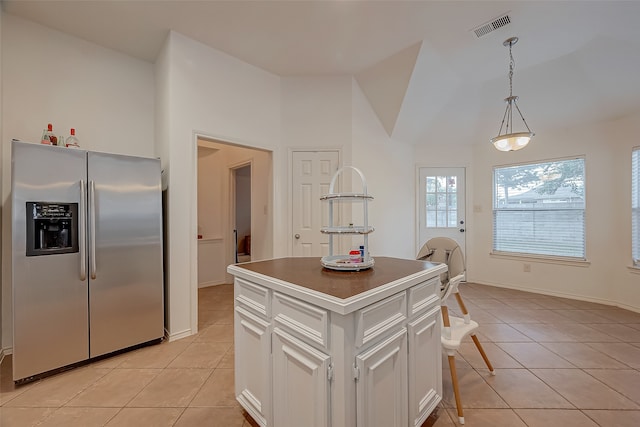 kitchen with a kitchen island, vaulted ceiling, stainless steel fridge with ice dispenser, white cabinetry, and light tile patterned flooring