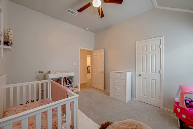 carpeted bedroom with ceiling fan, a nursery area, and vaulted ceiling