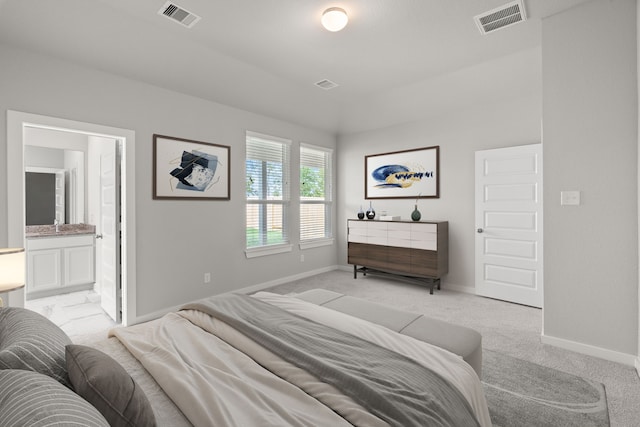 bedroom with ensuite bathroom and light colored carpet