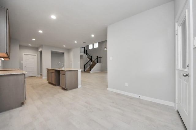 kitchen featuring a center island with sink, ceiling fan, light hardwood / wood-style floors, and sink