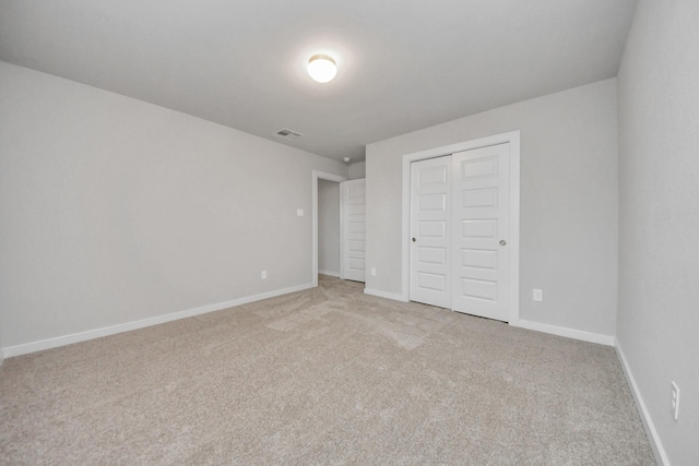 unfurnished bedroom featuring light colored carpet and a closet