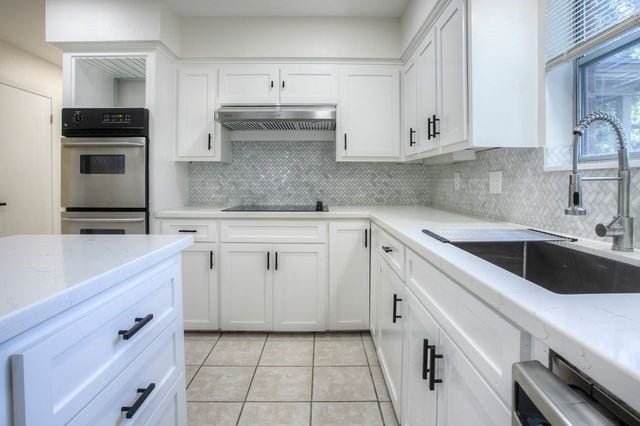 kitchen with tasteful backsplash, extractor fan, sink, white cabinetry, and light stone counters