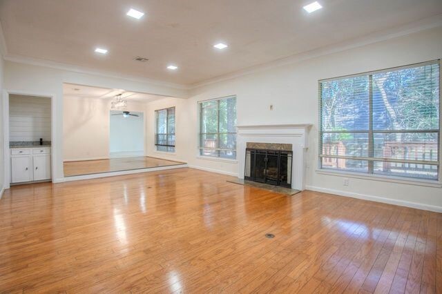 unfurnished living room featuring a healthy amount of sunlight, crown molding, and hardwood / wood-style flooring