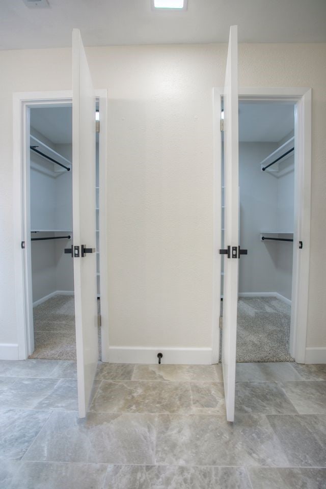bathroom with stone finish floor, baseboards, and a spacious closet