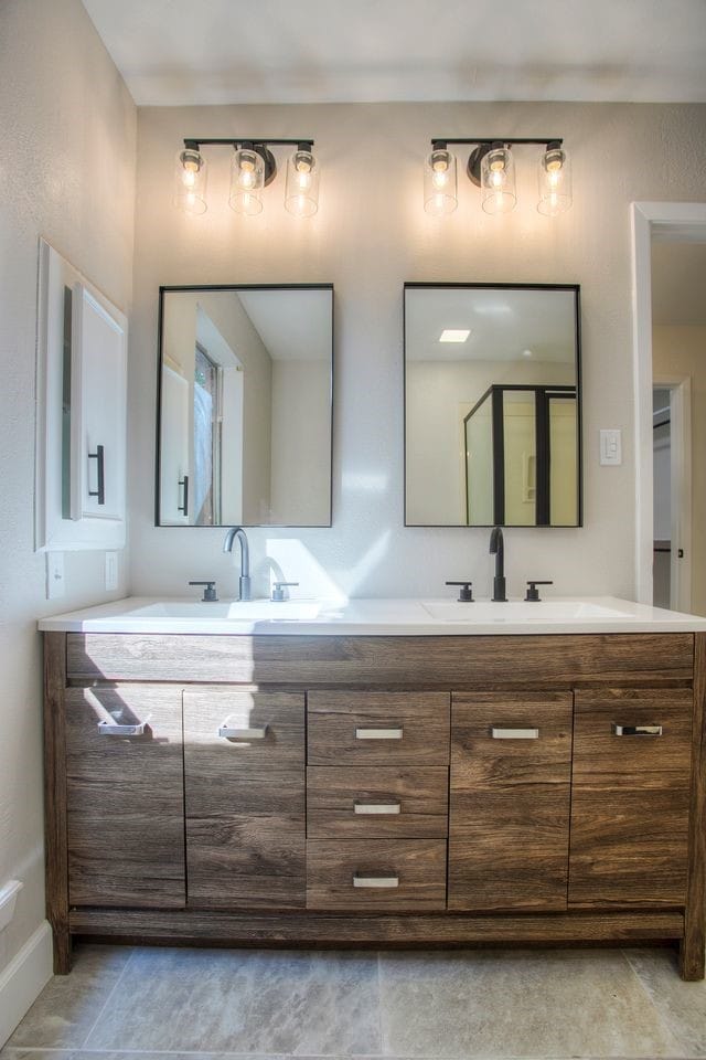 full bath featuring baseboards, a sink, and double vanity