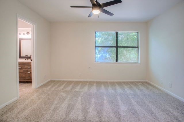 unfurnished room featuring a ceiling fan, baseboards, and light carpet