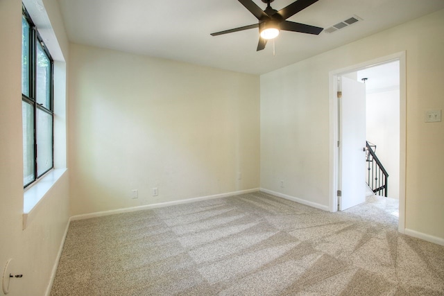 carpeted spare room with baseboards, visible vents, and ceiling fan