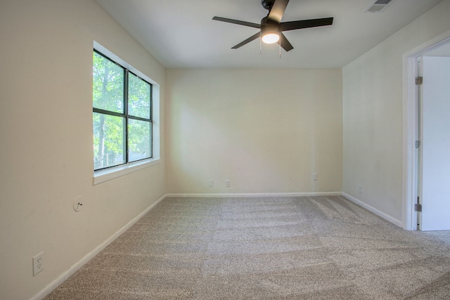 carpeted empty room featuring visible vents, a ceiling fan, and baseboards