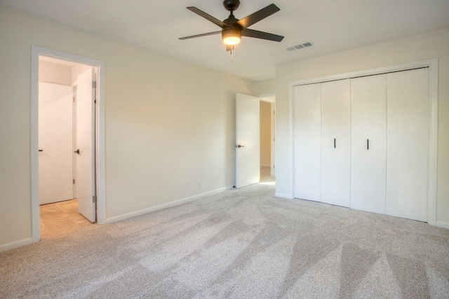 unfurnished bedroom featuring light carpet, visible vents, baseboards, a ceiling fan, and a closet