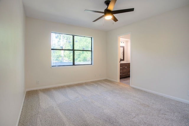 unfurnished bedroom with light colored carpet, ensuite bath, and ceiling fan