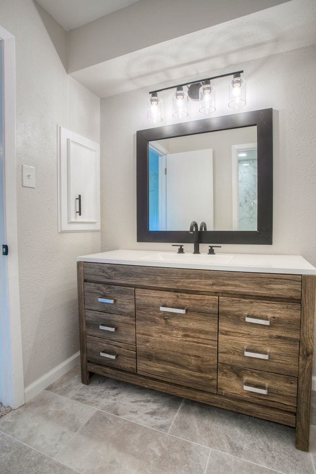 bathroom with a textured wall, vanity, and baseboards