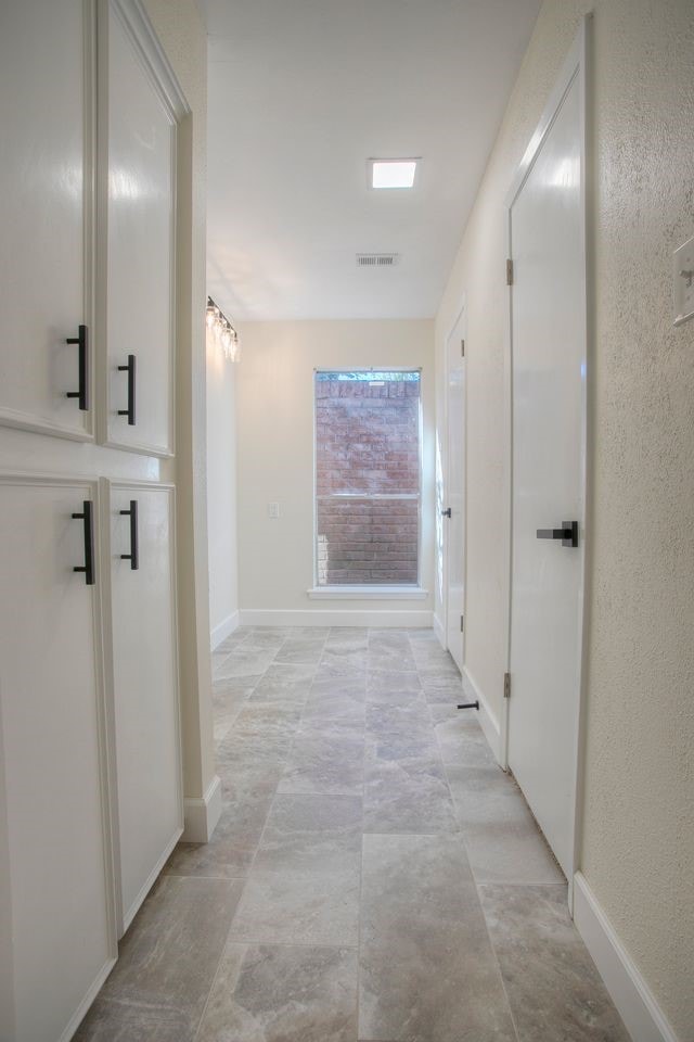 hallway featuring baseboards and visible vents