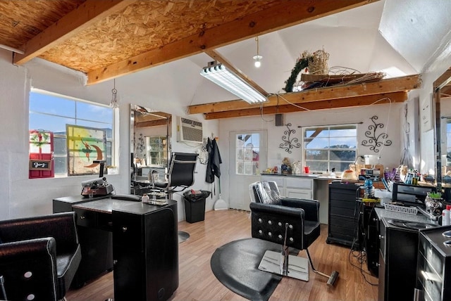 office space featuring a wall mounted AC, lofted ceiling with beams, and light hardwood / wood-style flooring