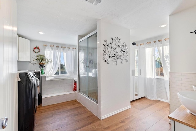 bathroom with hardwood / wood-style floors, walk in shower, washing machine and clothes dryer, and vanity